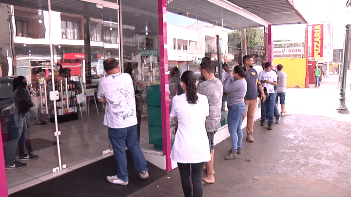 Pessoas fazem filas para comprar álcool em gel em loja da cidade